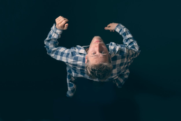 Handsome young male levitate in air on dark background b