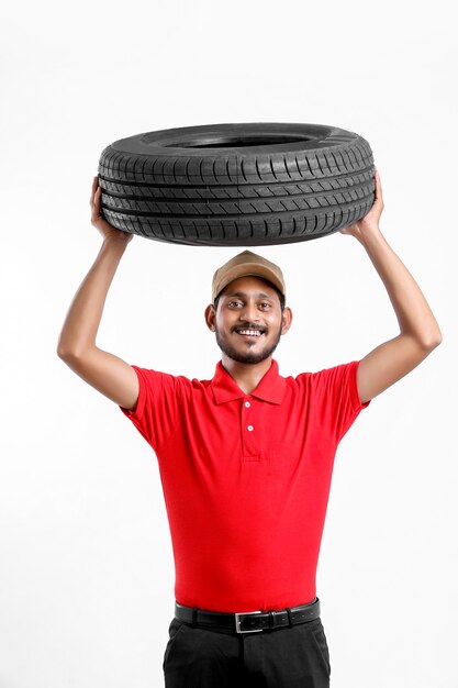 Handsome young male mechanic with new tires isolated on white background.