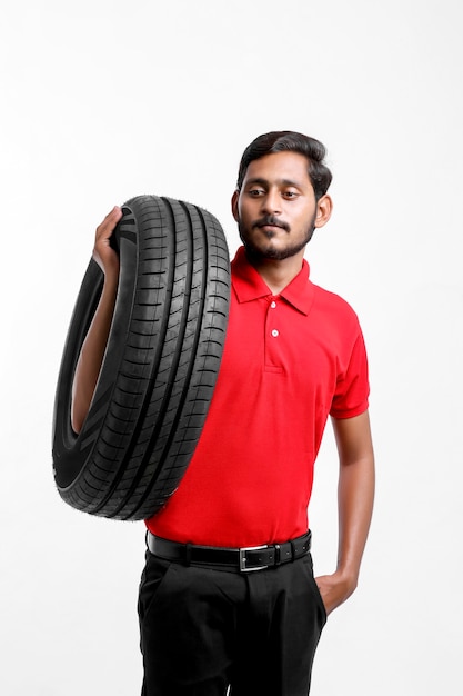 Handsome young male mechanic with new tires isolated on white background.