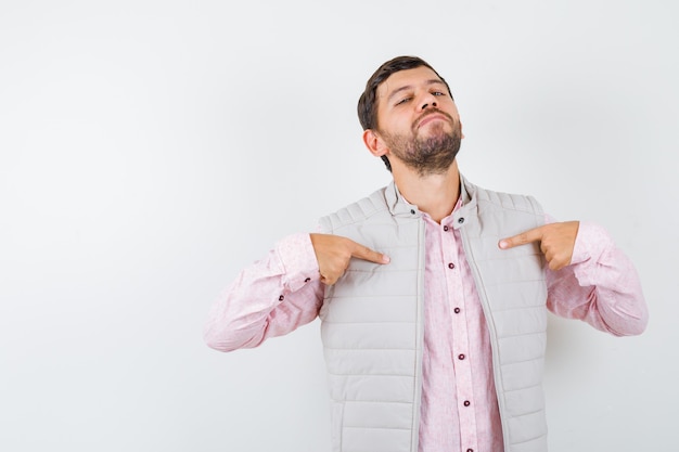 Handsome young male pointing at himself in shirt, vest and looking proud. front view.