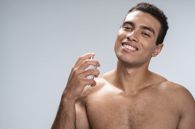 Handsome young male smiling perfuming himself after shower