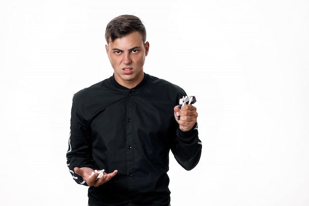 Handsome young man against smoking. The guy poses with broken cigarettes in his hands on an isolated background