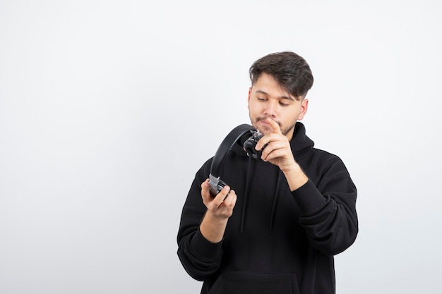 Handsome young man in black hoodie wearing big wireless music headphones 