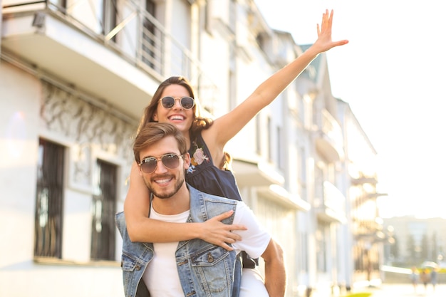 Handsome young man carrying young attractive woman on shoulders while spending time together outdoors.