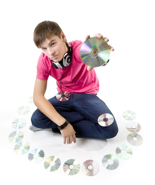 Handsome young man in casual clothes and headphones holds CD in his hands next to other CDs