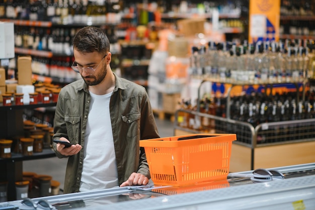 Un bel giovane che sceglie cibo al supermercato.