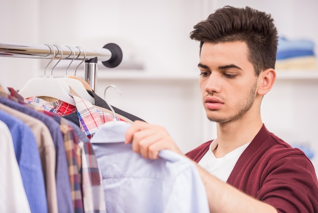 Handsome young man choosing shirt in the wardrobe.