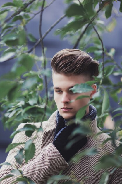 Handsome young man in coat on posing in park