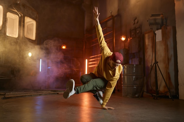 Photo handsome young man dancing hip hop movements breakdancing over urban studio background