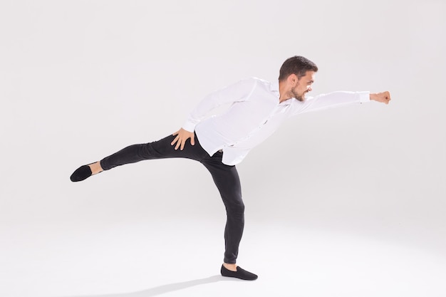 Photo handsome young man dancing on white wall