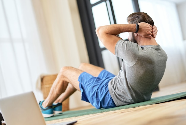 Handsome young man doing abs exercise at home