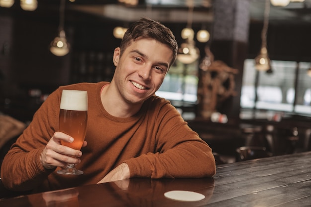 Giovane bello che beve birra al bar