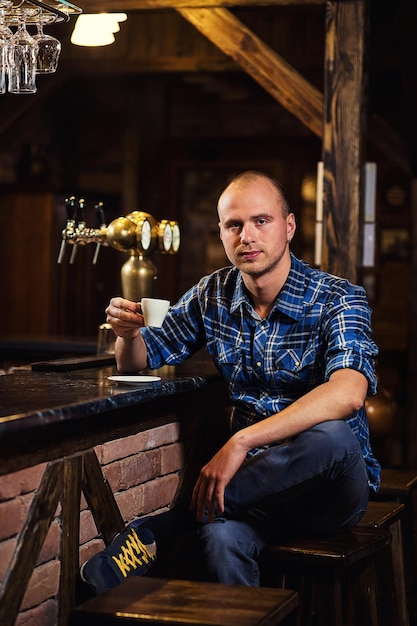 Handsome young man drinking and enjoying coffee while sitting\
at bar counter in city cafe