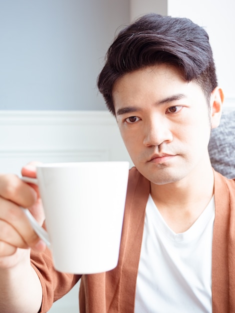 Handsome young man drinking at home