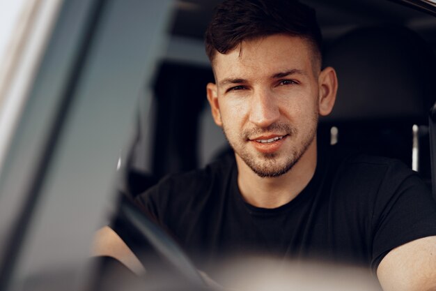 Photo handsome young man driver looking through the window of his off-road car