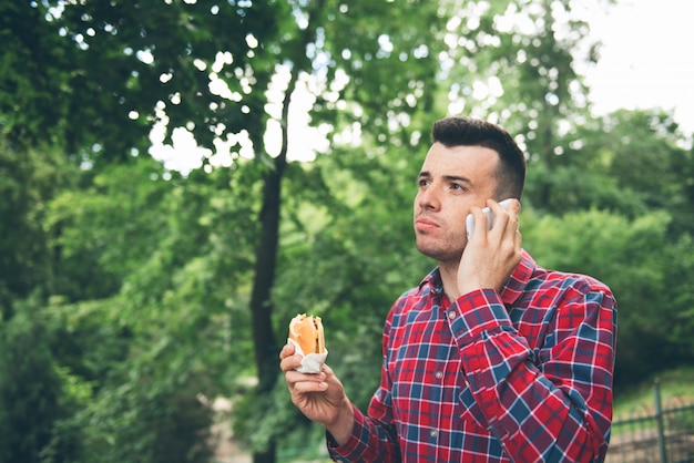 屋外のサンドイッチを食べてハンサムな若い男