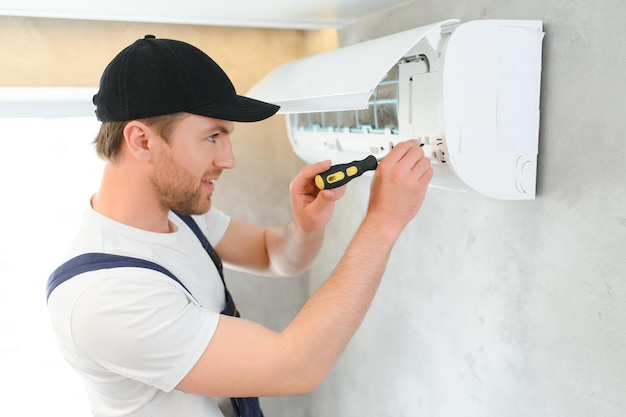 Photo handsome young man electrician installing air conditioning in a client house