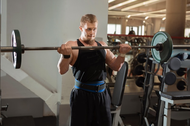 handsome young man exercising with a barbell in the gym
