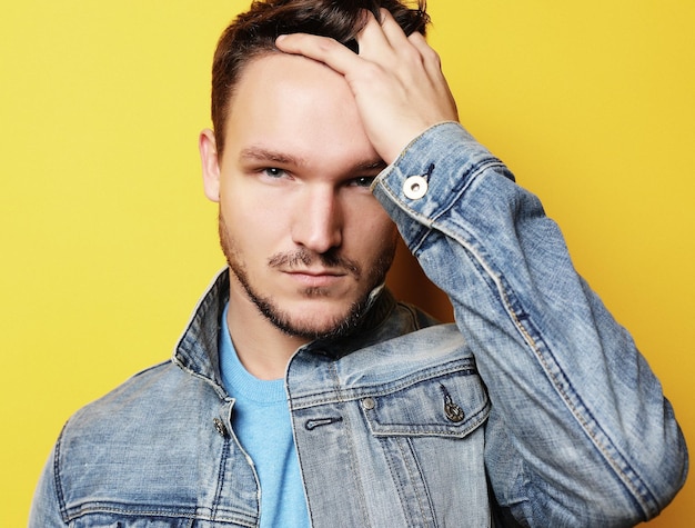 Handsome young man fashion model Posing over yellow wall Lifestyle and fashion concept