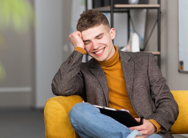 Handsome young man fills out a form sitting in the office on a chair