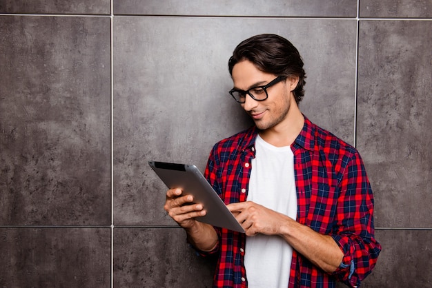 Bel giovane con gli occhiali utilizzando la tavoletta digitale