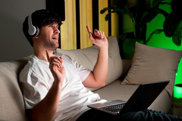 Handsome young man in a good mood enjoys music with headphones using a laptop has fun and relaxes af