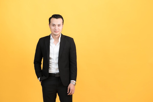 The handsome young man in a good mood standing on yellow background