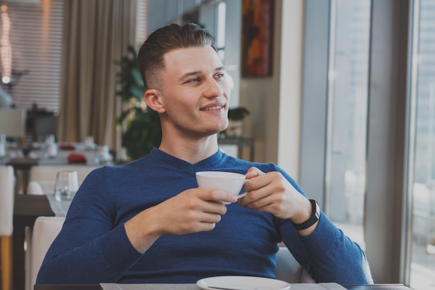 カフェで朝食を持っているハンサムな若い男