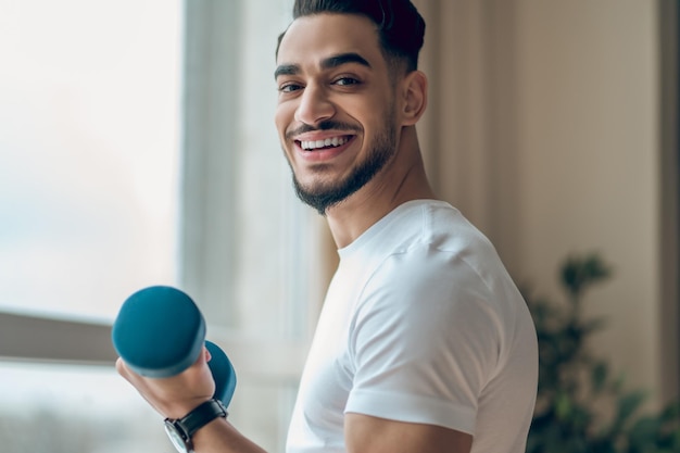 Giovane bello che ha un allenamento con i manubri