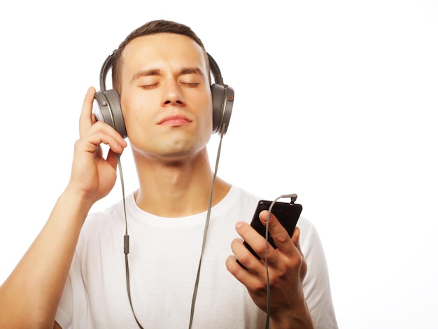 Handsome young man in headphones while standing against white background