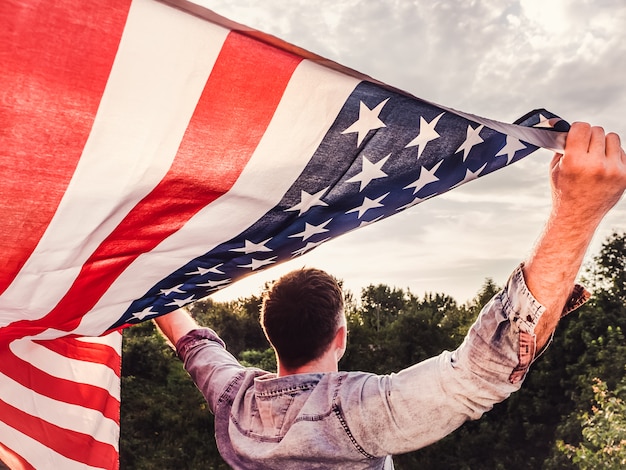 Foto bello, giovane che tiene una bandiera americana