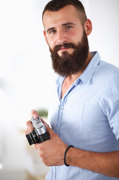 Handsome young man holding digital camera on white background