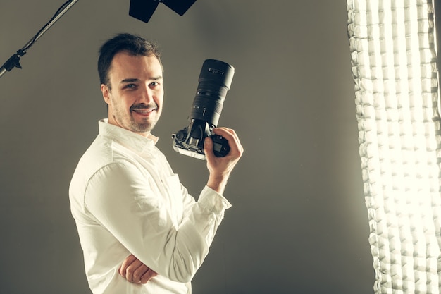 Handsome young man holding a DSLR camera.