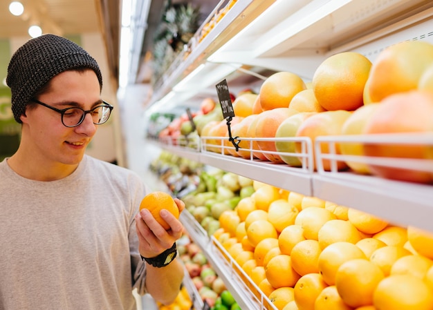 Handsome young man holds orange