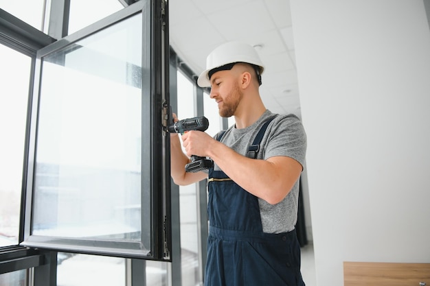 Handsome young man installing bay window in new house construction site