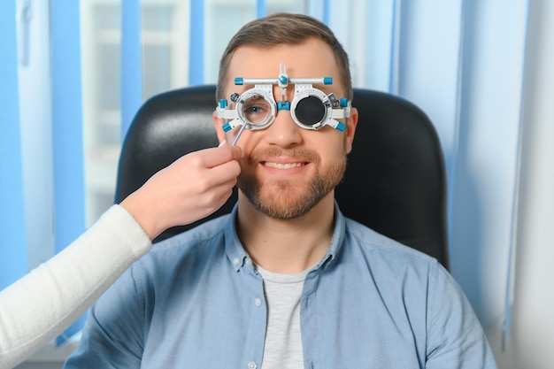 ハンサムな若い男は、現代の眼科クリニックで目の視力をチェックしています 眼科クリニックの患者