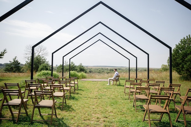 Handsome young man is sitting in meditation before the wedding ceremony in the air open space.