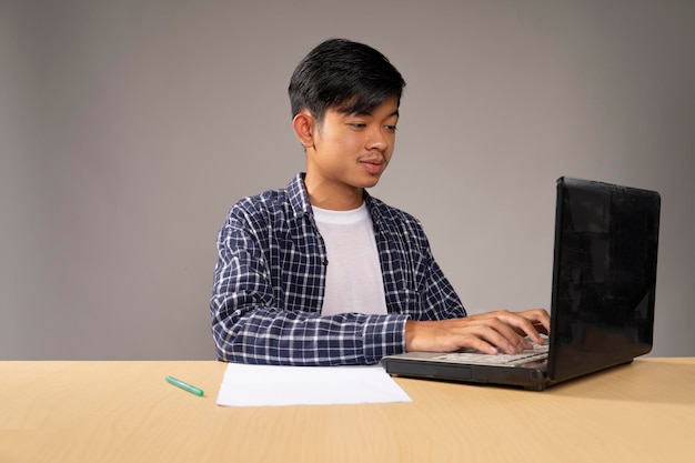 Красивый молодой человек печатает на своем ноутбуке с фокусом Карантин и концепция социального дистанцирования