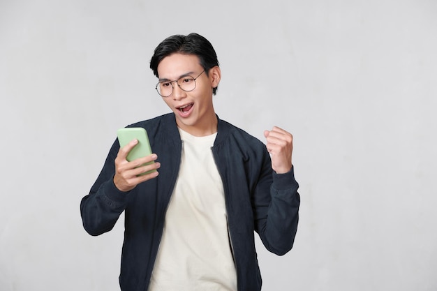 Handsome young man over isolated background with phone in victory position