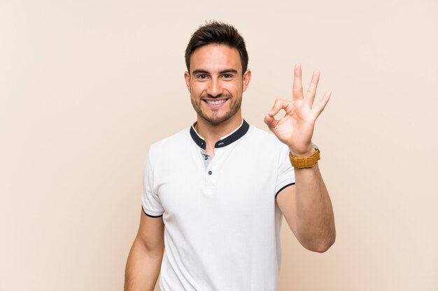 Handsome young man over isolated showing ok sign with fingers