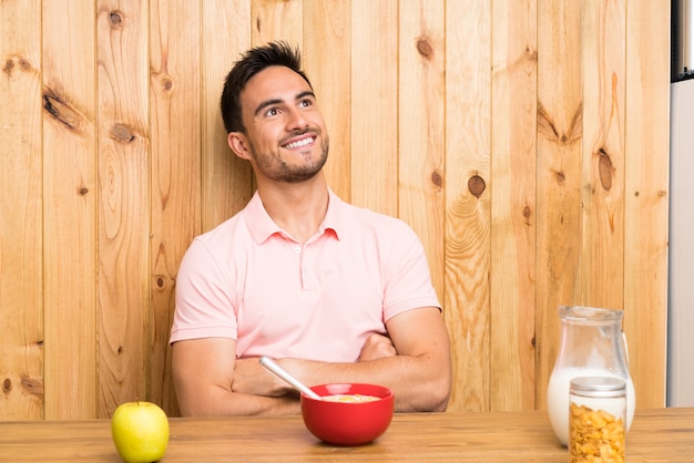 Handsome young man in a kitchen having breakfast looking up while smiling