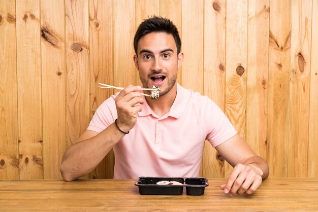 Handsome young man in a kitchen with sushi