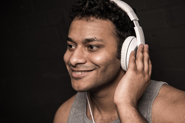 Handsome young man listening music in headphones isolated on black