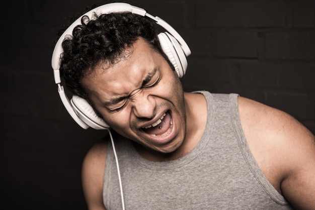 Handsome young man listening music in headphones isolated on black