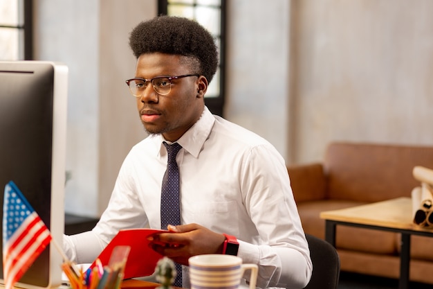  Handsome young man looking at the computer screen while being focused on his work