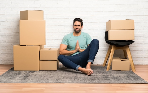 Handsome young man moving in new home among boxes pleading