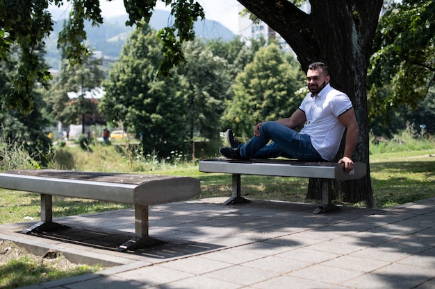 Handsome Young Man in Park Sitting on Bench