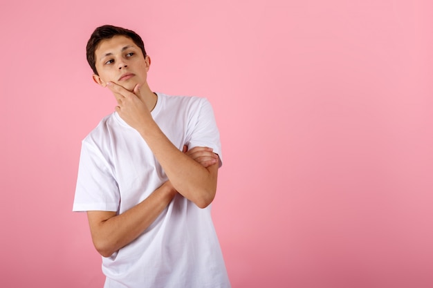 Handsome young man on pink background thinking an idea