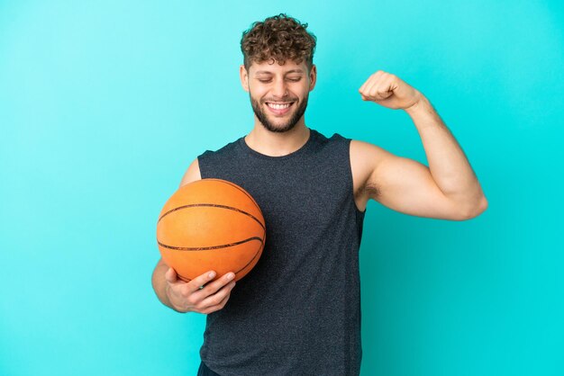 Красивый молодой человек, играющий в баскетбол на синем фоне, делает сильный жест