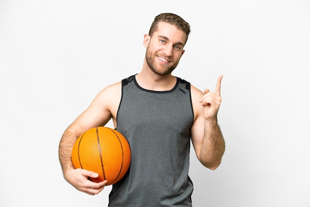 Handsome young man playing basketball over isolated white background showing and lifting a finger in sign of the best